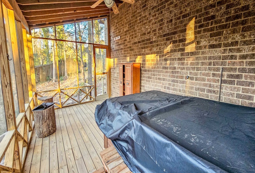 Screened porch featuring wood-finish flooring, a brick accent wall, and a ceiling fan