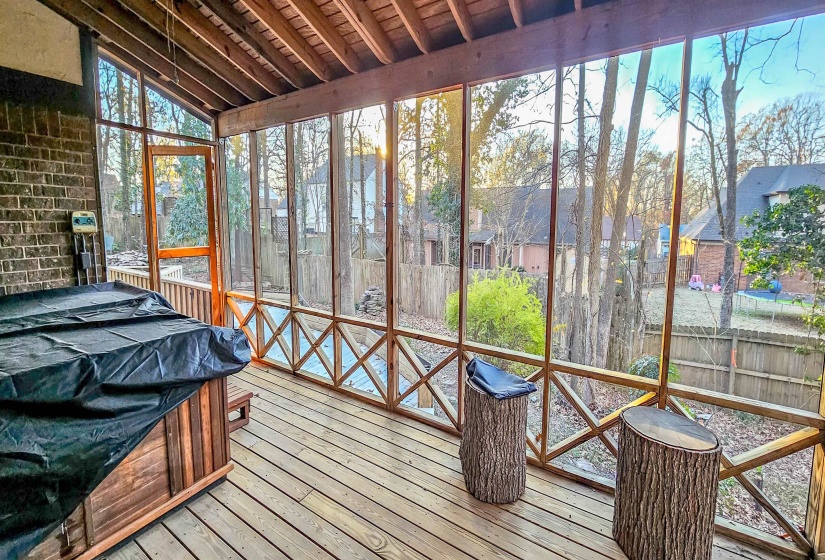 Screened porch featuring wood-finish flooring, exposed beam ceiling, brick exterior wall, and a hot tub