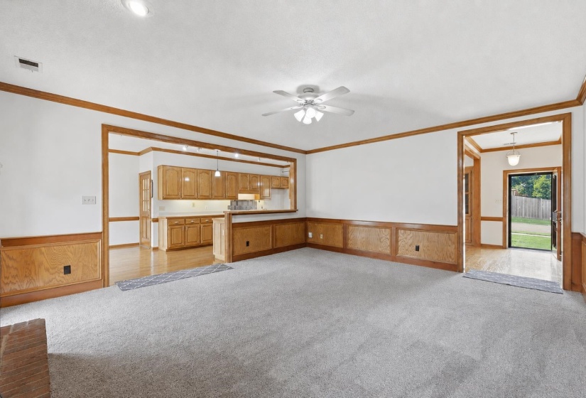 Spacious living area featuring light gray carpeting, white walls, and wood trim with wainscoting