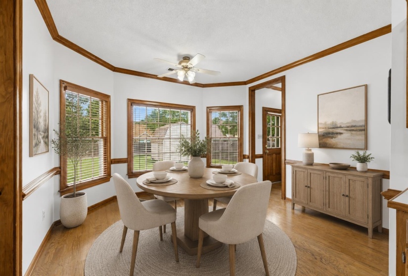 Eat-in area with wood-finish flooring, light walls, and rich wood trim. Furniture is virtually staged.