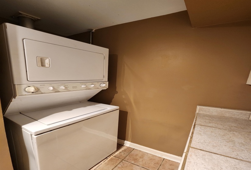 White stacked laundry units feature a top-load washer and front-load dryer