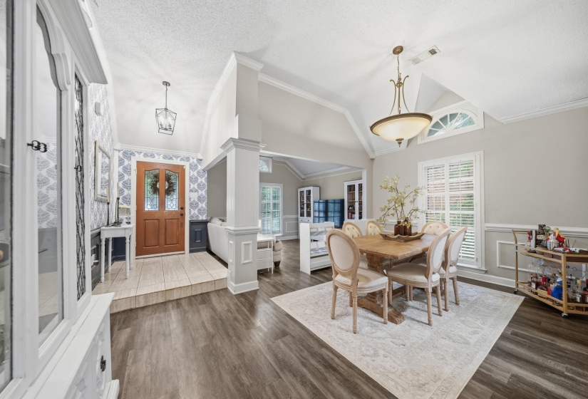Spacious interior featuring wood-finish flooring, vaulted ceilings, and a decorative wall paneling