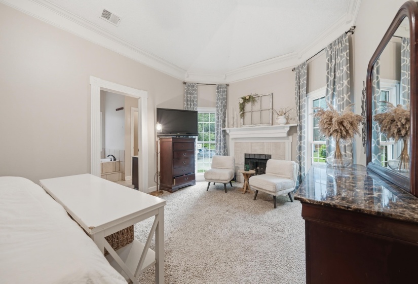 Carpeted room featuring a fireplace with a light-toned tile surround, vaulted ceiling, and multiple windows