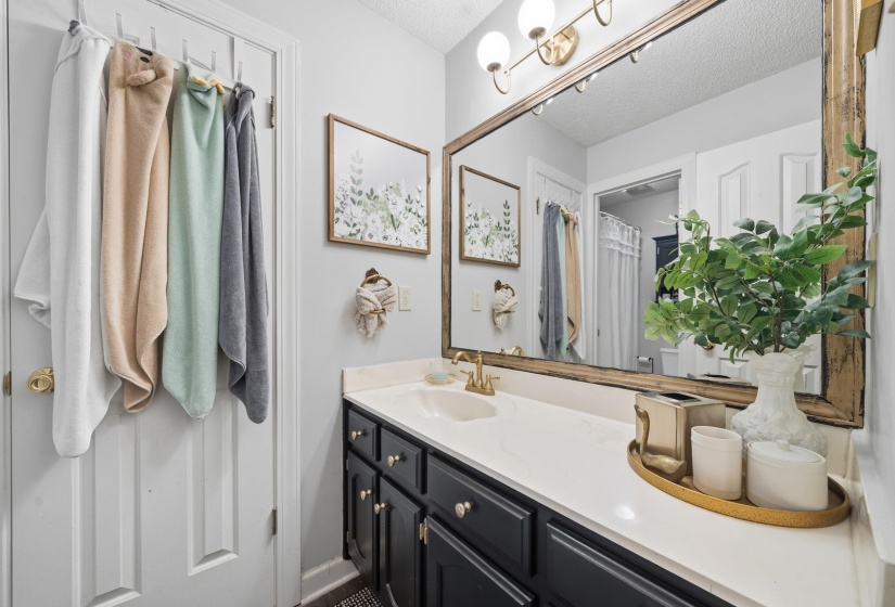 Bathroom vanity featuring a single basin, gold-finish faucet, and white countertop