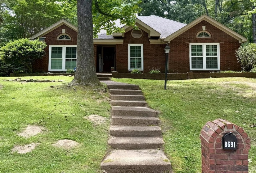 Brick exterior with a gabled roofline, featuring an integrated brick mailbox and a lamp post