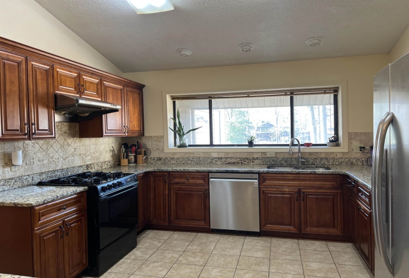 Kitchen with a sink, a wealth of natural light, under cabinet range hood, and stainless steel appliances