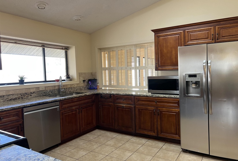 Kitchen with stainless steel appliances, light tile patterned flooring, Granite counters, and lofted ceiling