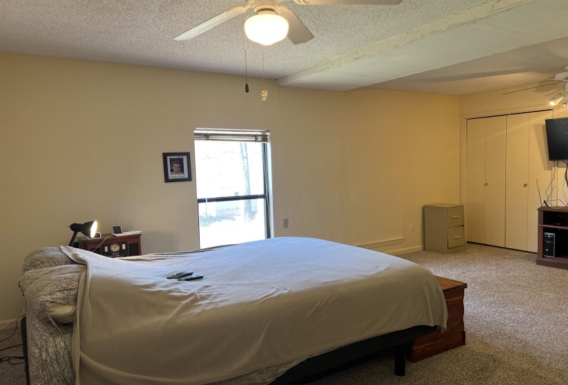 Carpeted bedroom with a textured ceiling and ceiling fan