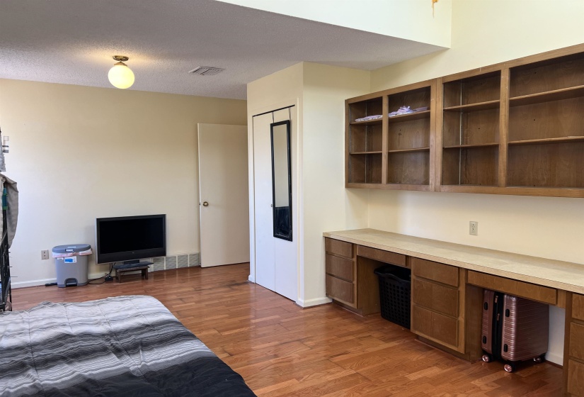 Bedroom with visible vents, a textured ceiling, built in study area, and light wood-style floors