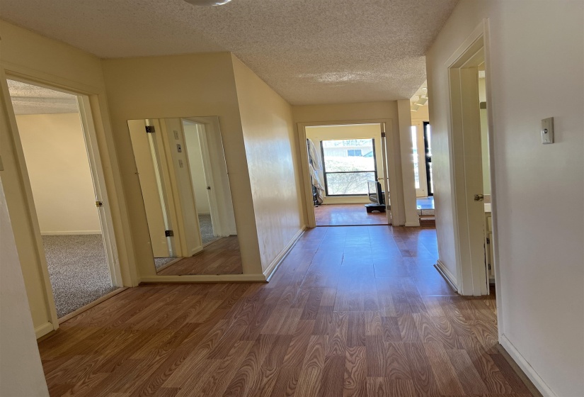 Hall featuring a textured ceiling, baseboards, and wood finished floors