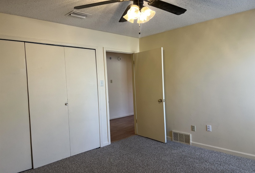 Bedroom featuring a closet, visible vents, a textured ceiling, and carpet