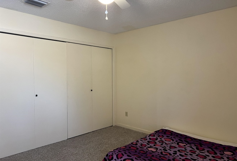 Bedroom with visible vents, carpet, a closet, a textured ceiling, and a ceiling fan