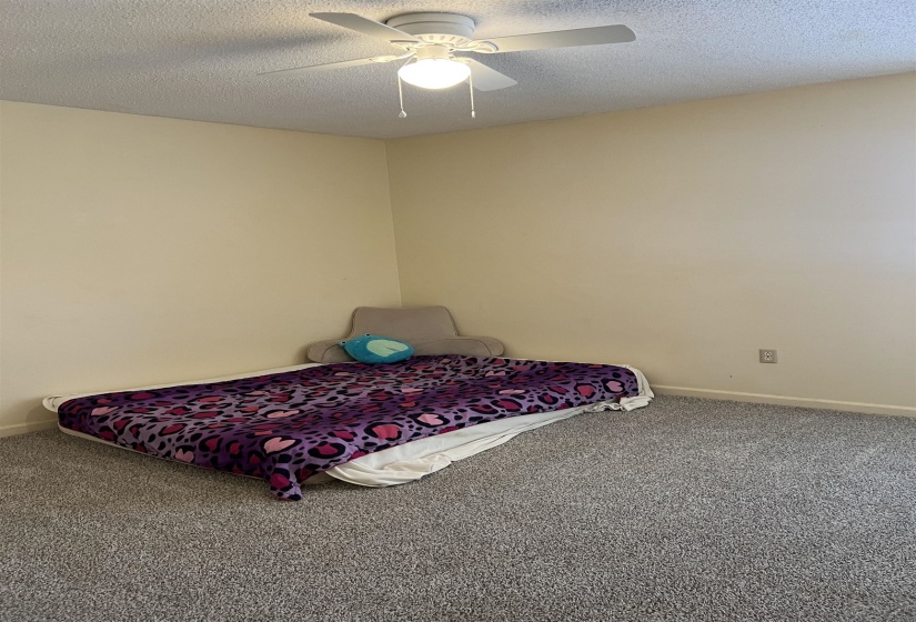 Bedroom featuring baseboards, a textured ceiling, carpet, and a ceiling fan