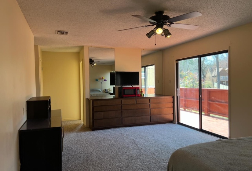 Carpeted bedroom featuring visible vents, a textured ceiling, a ceiling fan, and access to outside