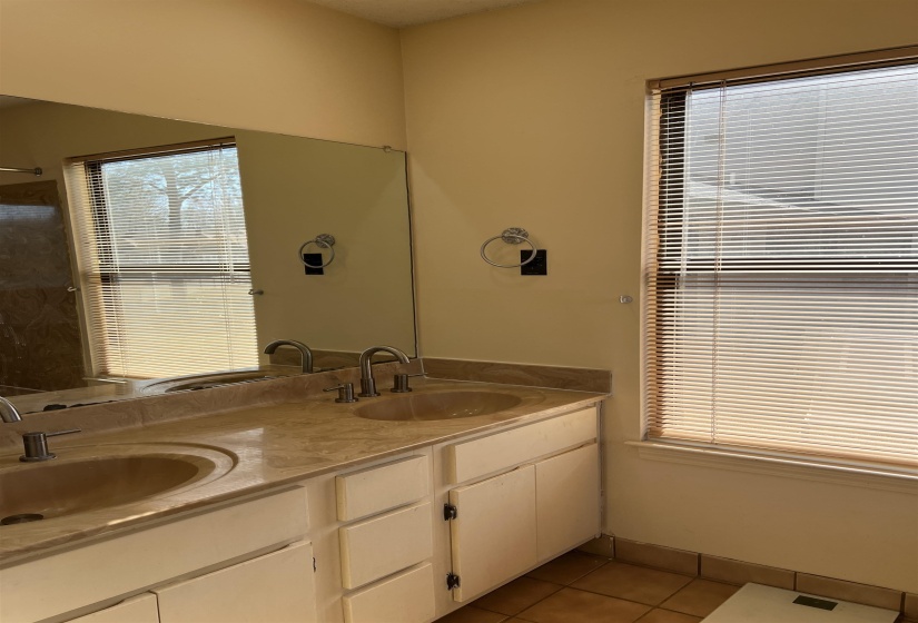 Bathroom featuring tile patterned floors, double vanity, baseboards, and a sink