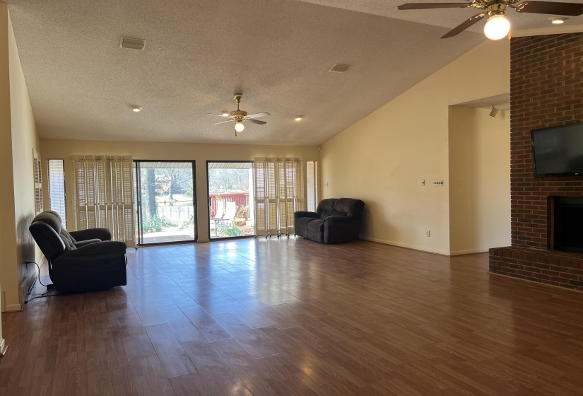 Unfurnished living room featuring dark wood finished floors, visible vents, a fireplace, and a ceiling fan