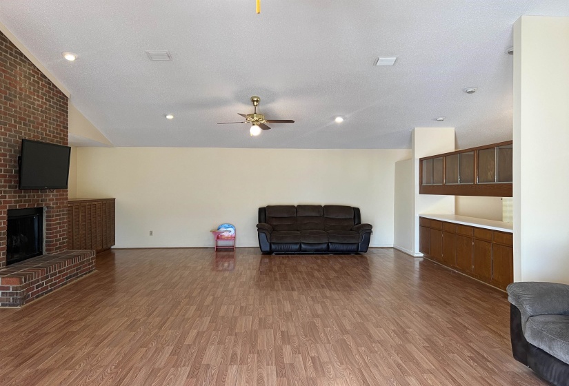Interior space with visible vents, a ceiling fan, a textured ceiling, wood finished floors, and a fireplace