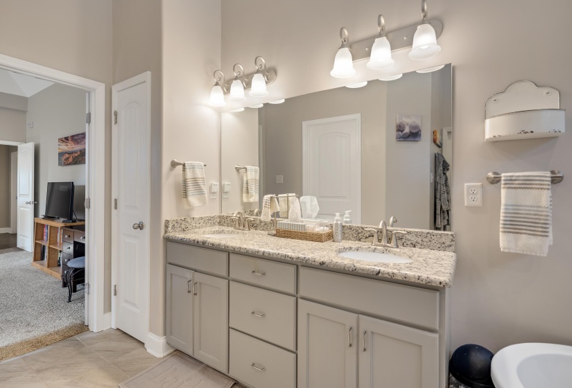 Double vanity with light-toned cabinetry and stone-finish countertops, featuring dual undermount sinks and brushed nickel faucets