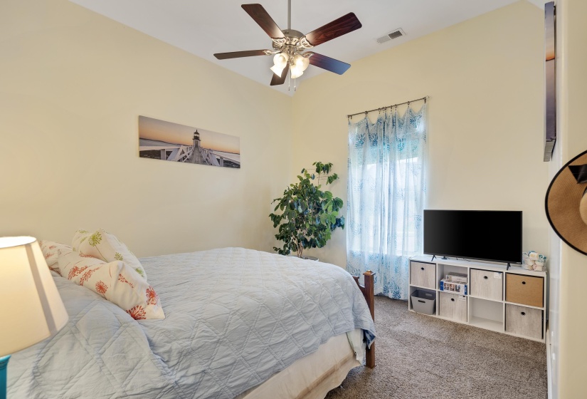 Vaulted ceilings featuring a ceiling fan with integrated lighting, carpet flooring, and a window with natural light