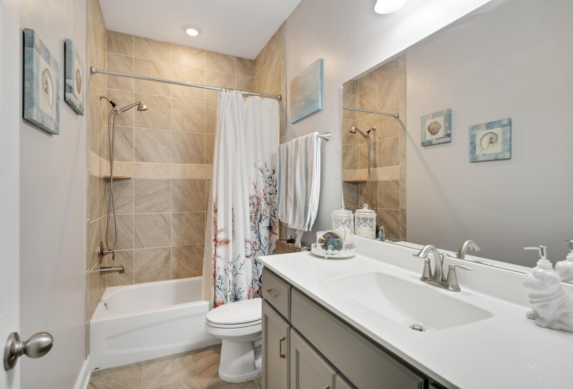 Bathroom featuring a built-in tub with a tiled shower surround, recessed shower niche, and a brushed nickel showerhead