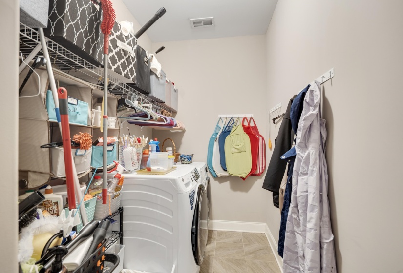 Laundry area featuring a front-loading washer, wire shelving, light-toned wall paint, and tile flooring