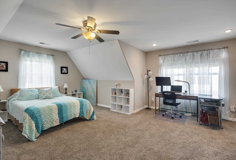 Carpeted room featuring a ceiling fan with integrated lighting, recessed lighting, and an angled ceiling detail