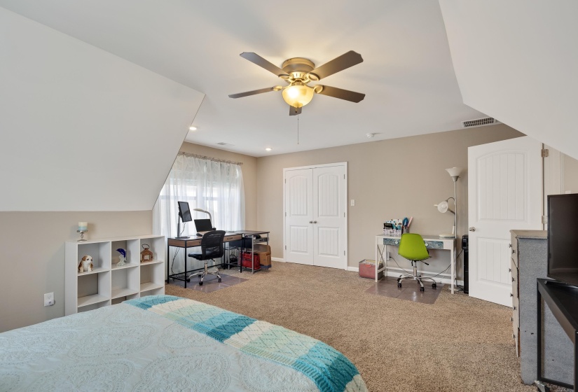 Carpeted bedroom with a sloped ceiling and recessed lighting