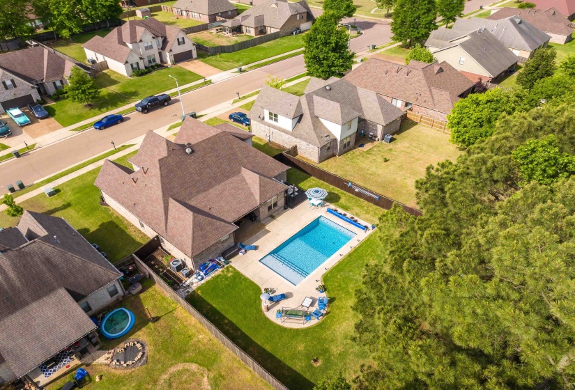 Expansive backyard featuring a rectangular swimming pool, concrete patio, and a privacy fence