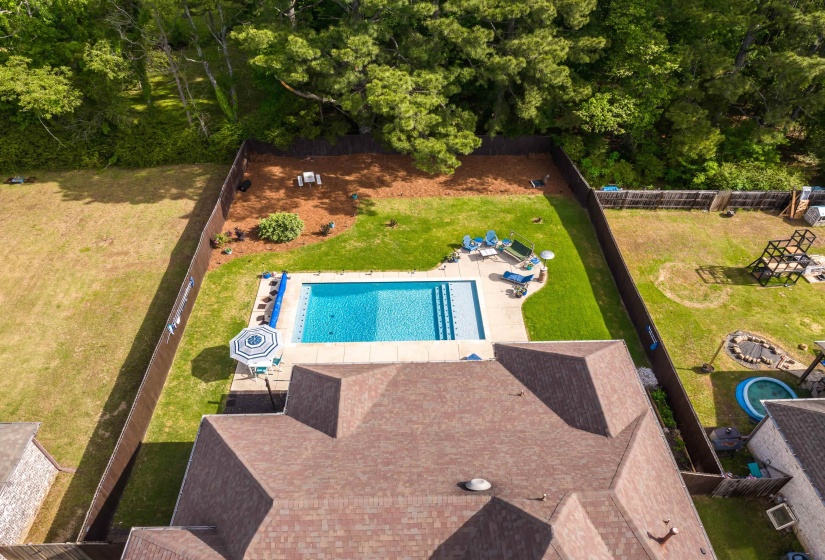 Aerial view showcasing a rectangular swimming pool with integrated steps, surrounded by a concrete patio and manicured lawn