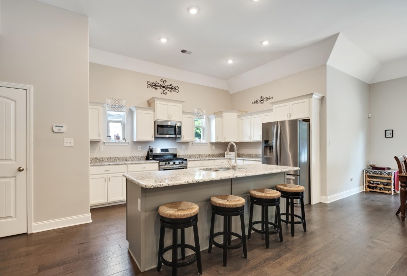 Spacious kitchen featuring white cabinetry, stainless steel appliances, granite countertops, and a large island with seating