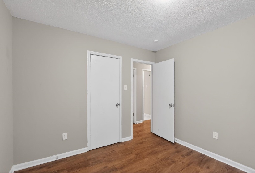 Neutral gray wall paint with white trim, wood-finish flooring, and white interior doors with chrome hardware