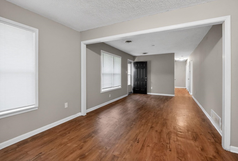 Expansive room featuring wood-finish flooring, neutral gray walls, white trim, and multiple windows with blinds