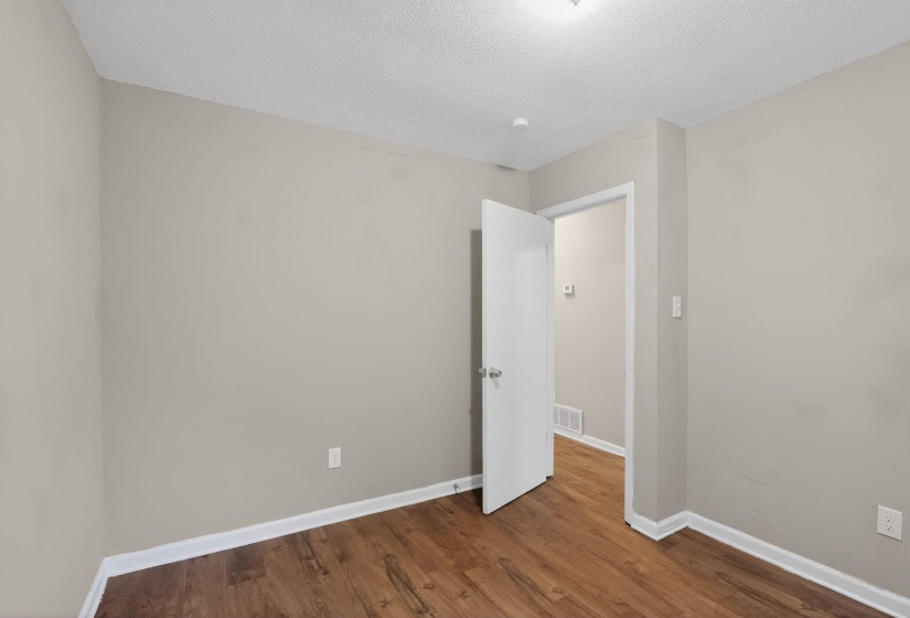 Interior room featuring wood-finish flooring, light neutral wall paint, and white trim molding