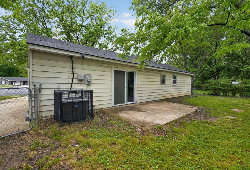 Rear exterior featuring a concrete patio, sliding glass door, and two rear windows
