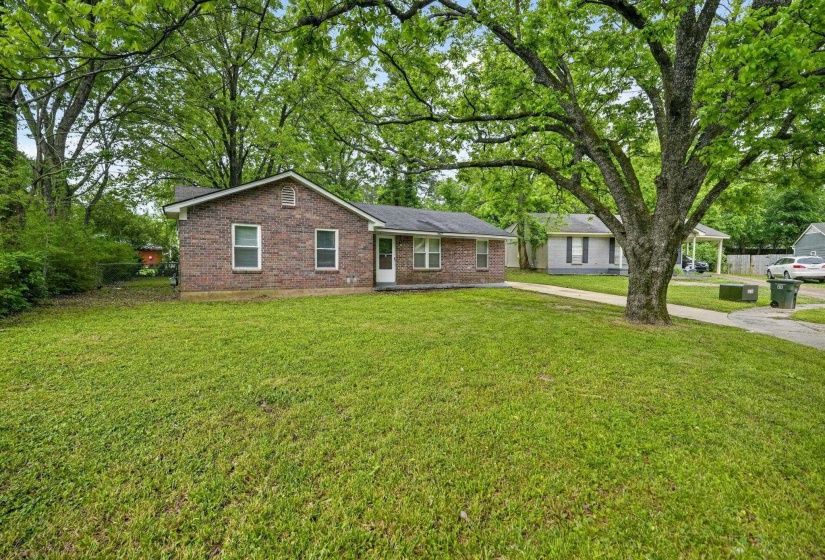 Brick exterior ranch home featuring a dark shingle roof and white window trim