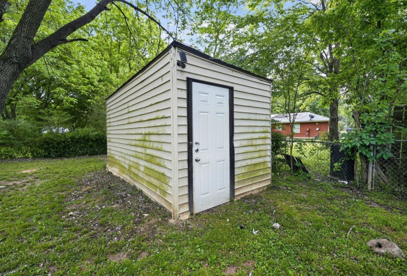Detached storage shed with white siding and a white entry door