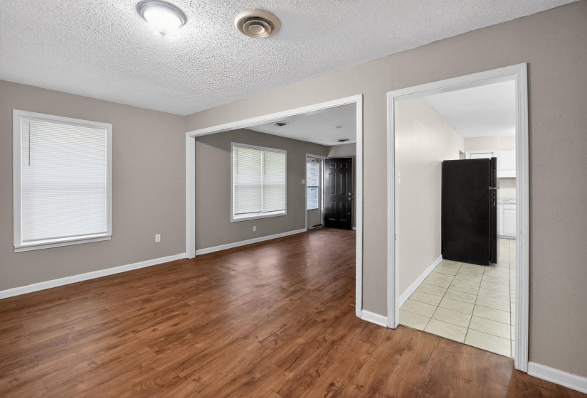 Open-concept living area featuring wood-finish flooring, neutral wall tones, and multiple windows with blinds