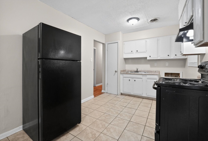 Kitchen featuring tile flooring, white cabinetry, a black oven range, black refrigerator, and a recessed ceiling light fixture