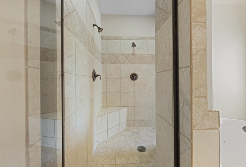 Walk-in shower with full tile surround, integrated bench seating, and bronze-finish fixtures