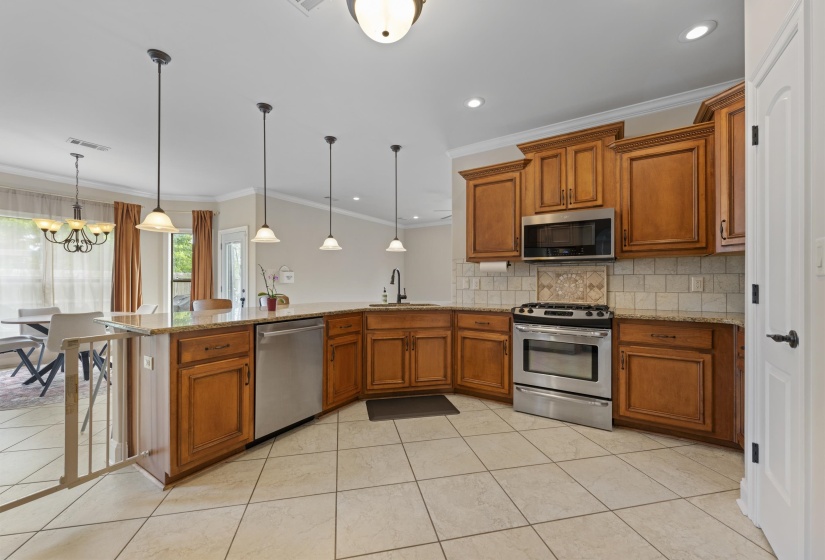 Kitchen featuring wood cabinetry, stainless steel appliances, a tile backsplash, and a breakfast bar with pendant lighting