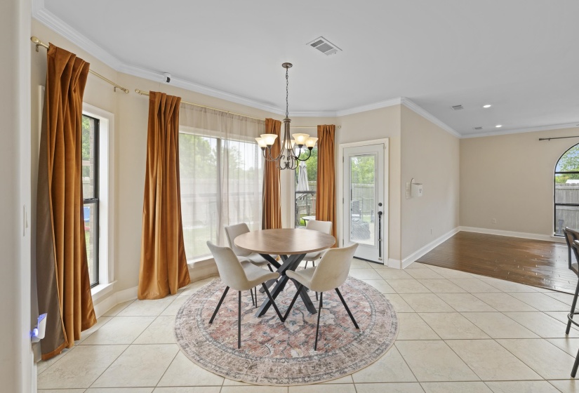 Dining area with large bay windows, crown molding, and neutral tile flooring