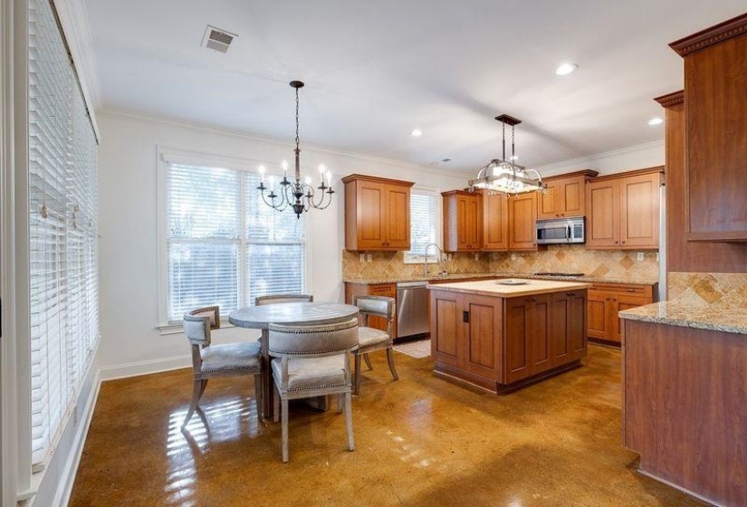 Kitchen with a kitchen island, decorative backsplash, stainless steel appliances, hanging light fixtures, and ornamental molding