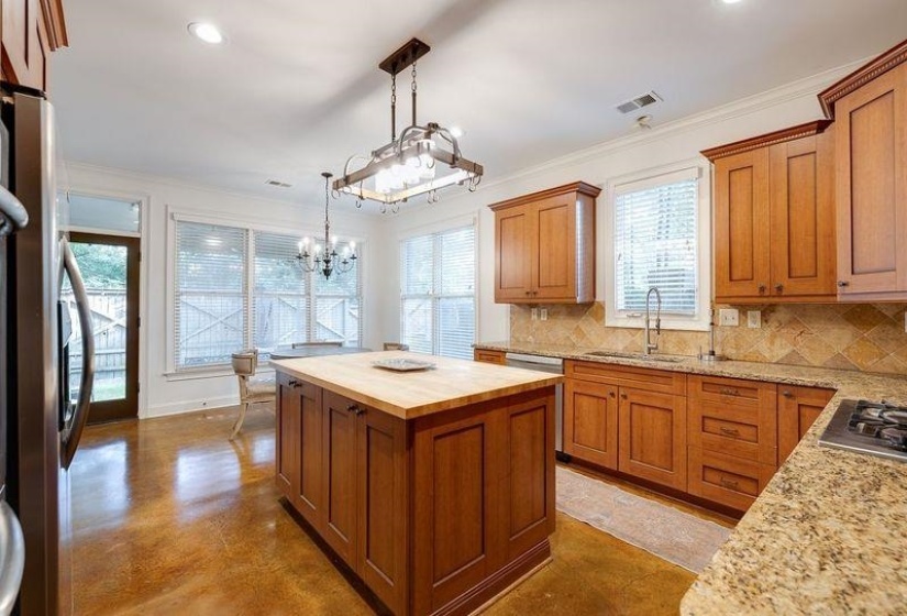 Kitchen with wooden counters, an inviting chandelier, tasteful backsplash, a kitchen island, and hanging light fixtures