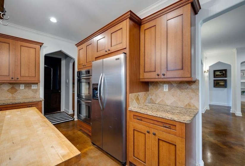 Kitchen featuring butcher block countertops, appliances with stainless steel finishes, ornamental molding, and decorative backsplash