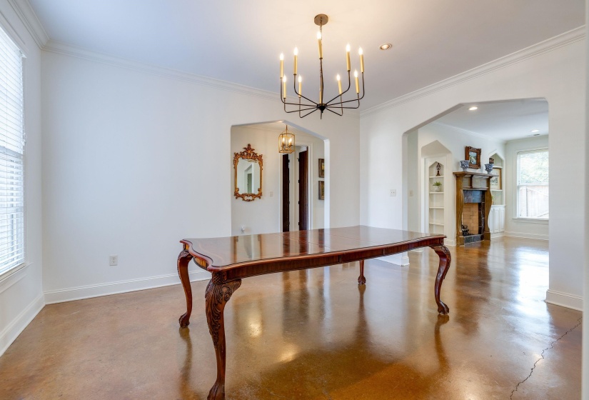 Dining room with concrete flooring, an inviting chandelier, and crown molding