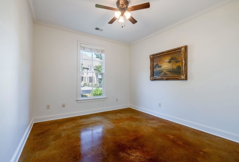 Downstairs bedroom with concrete floors, ornamental molding, and ceiling fan