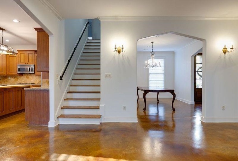 Stairway with ornamental molding, a chandelier, and concrete floors