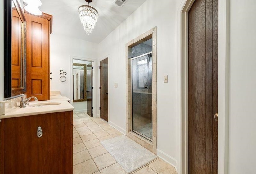 Primary Bathroom with walk in shower, tile patterned floors, a notable chandelier, and vanity