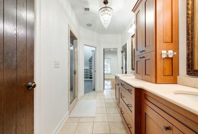 Bathroom featuring tile patterned flooring, walk in shower, a notable chandelier, and vanity