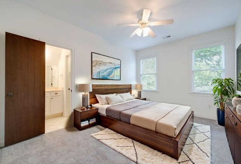Bedroom featuring light carpet, connected bathroom, and ceiling fan